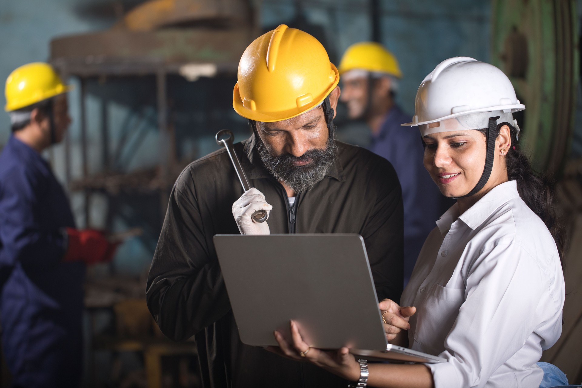 Mechanic and female engineer using laptop at factory